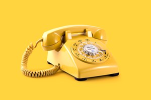 A yellow old fashioned dial telephone